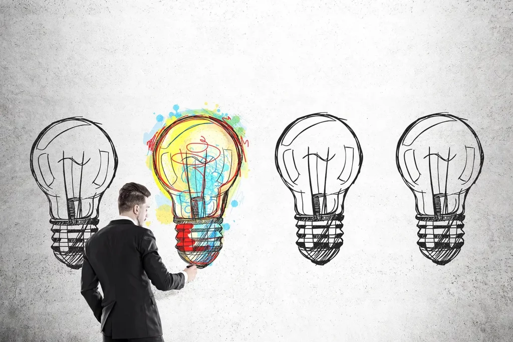 A man drawing lightbulbs and one is colorful